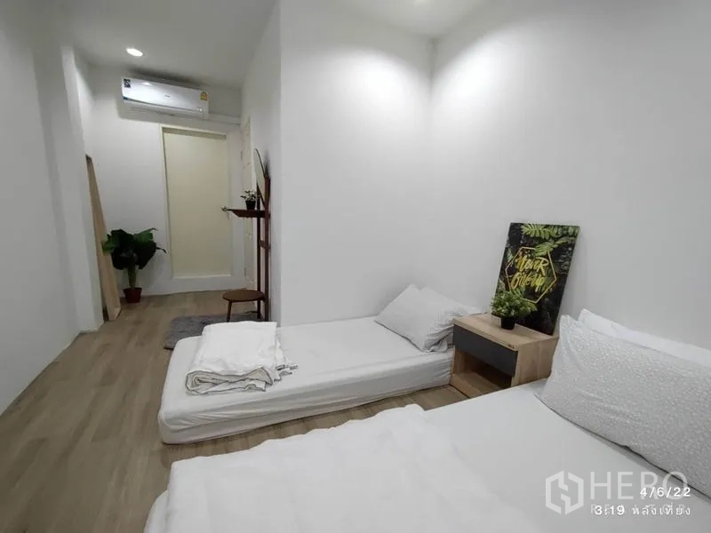 Home Office for rent - Second angle of slim bedroom with air conditioner, plants and bedside table décor.