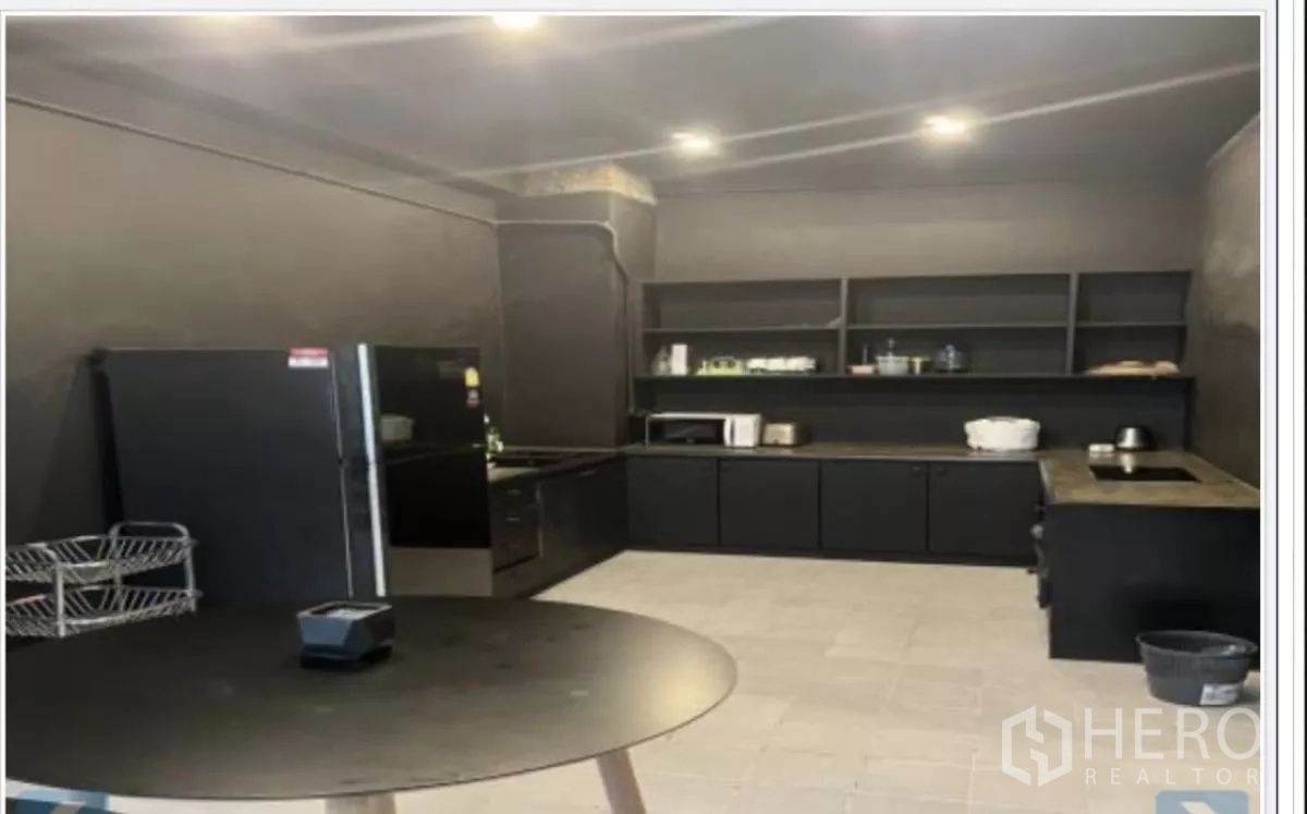 带办公室的家 出租在Wang Thonglang, Bangkok - 配置齐全的黑色橱柜厨房，开放式搁架与家电。