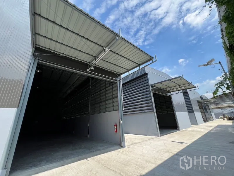 Warehouse for rent in Prawet, Bangkok - Open warehouse bay with metal canopy, grey facade and wide access suitable for trucks.
