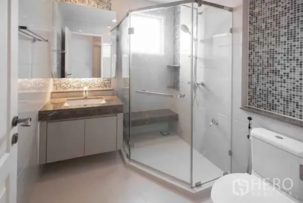 Detached House for rent or sale in Bang Phli, Samut Prakan - Modern bathroom with glass-enclosed shower, mosaic accent wall, vanity and toilet.