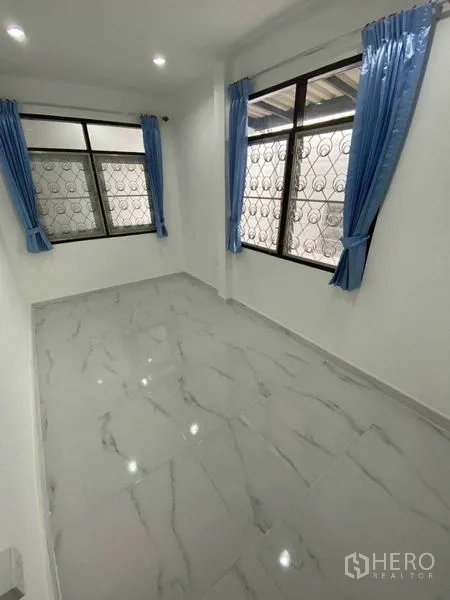 独立式住宅 出租在Huai Khwang, Bangkok - 明亮房间，大窗配蓝色窗帘与防盗格栅。