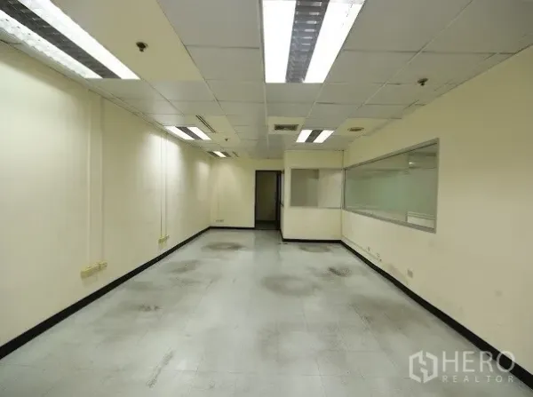 办公空间 出租在Watthana, Bangkok - 狭长工作区，带内部观察窗、天花灯与瓷砖地面。