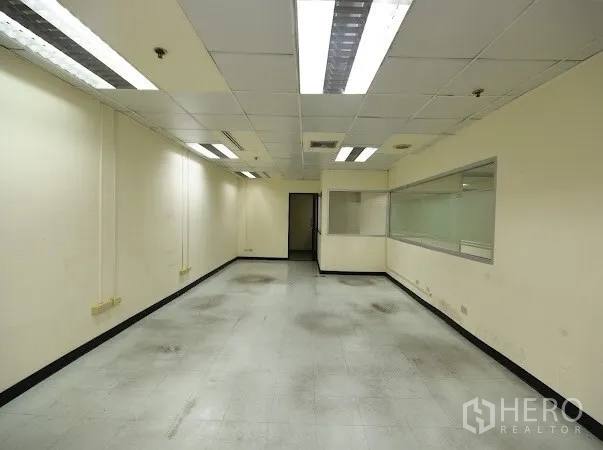 办公空间 出租在Watthana, Bangkok - 狭长工作区，带内部观察窗、天花灯与瓷砖地面。