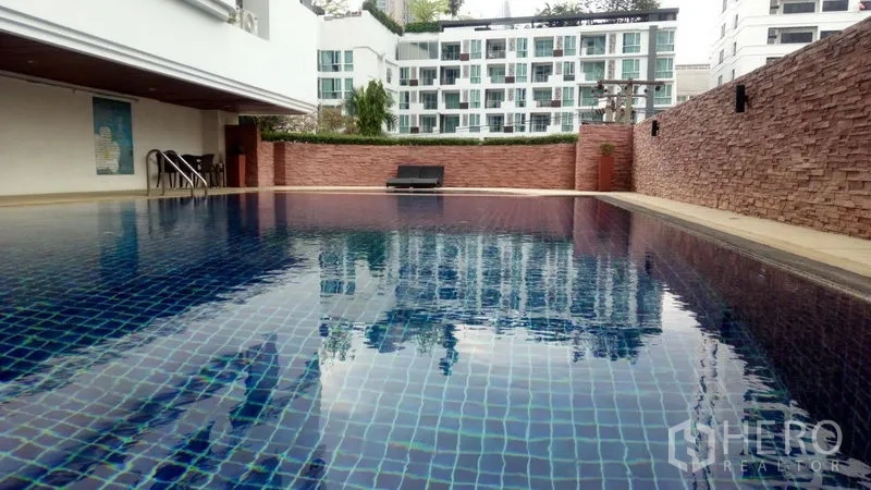 公寓 出租或出售在Watthana, Bangkok - 公寓蓝色马赛克室外泳池，配躺椅，周围为低层建筑。