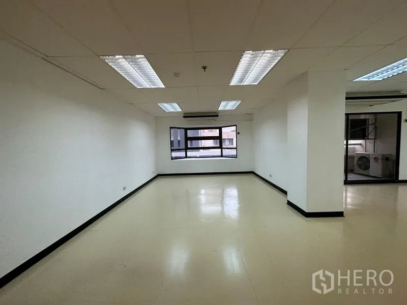 办公空间 出租在Pathum Wan, Bangkok - 空置办公室，吊顶与荧光灯，浅色地面，尽端有窗和空调。