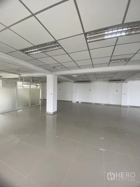 办公空间 出租在Khlong Toei, Bangkok - 开放式办公区，格栅吊顶、荧光灯、亮面地砖、立柱与玻璃隔断。