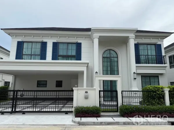 บ้าน ให้เช่าหรือขายในBang Phli, Samut Prakan - ด้านหน้าบ้านเดี่ยวสองชั้นสไตล์โมเดิร์นคลาสสิก มีบานเกล็ดสีน้ำเงิน ซุ้มประตูโค้ง และโรงจอดรถมีรั้ว