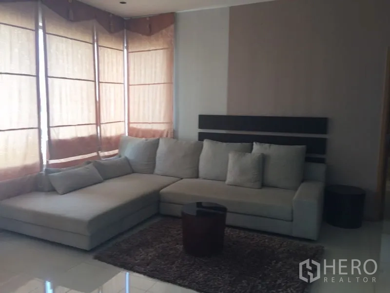 Condominium for rent - Cozy lounge area with sectional sofa and rug by bay windows with blinds.
