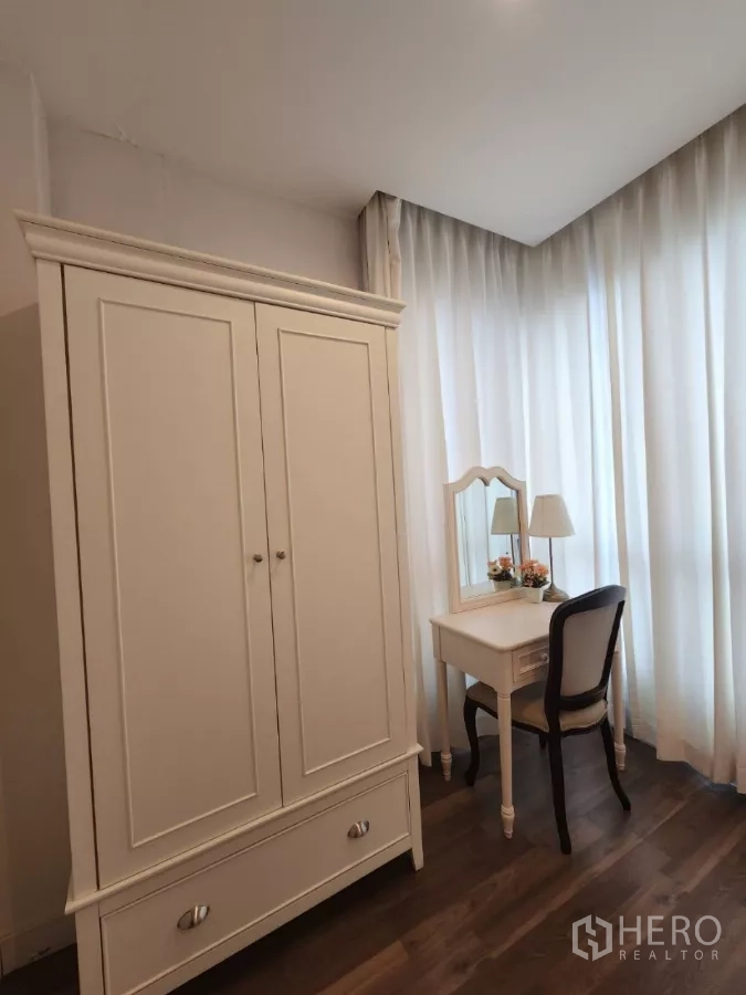Condominium for rent in Phra Khanong, Bangkok - Wardrobe and vanity set beside sheer corner windows.