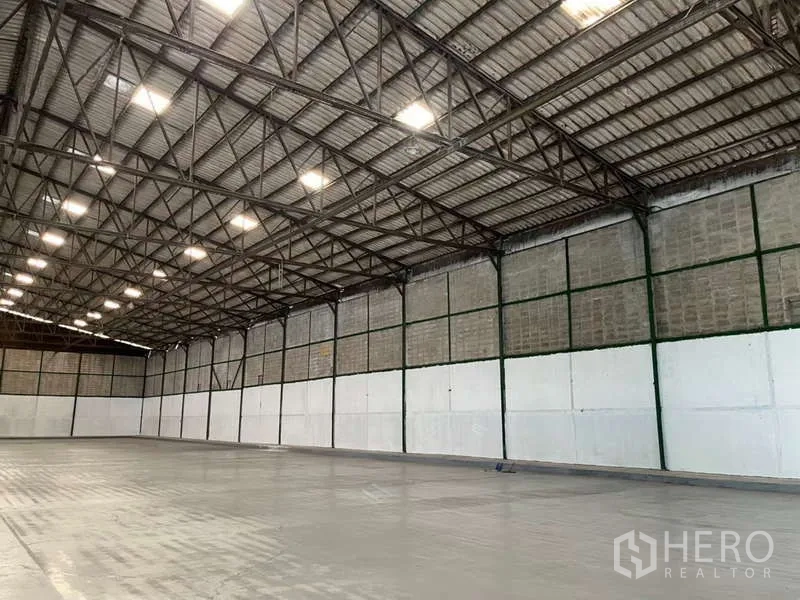 Factory for rent in Bang Pakong, Chachoengsao - Long interior wall lined with steel columns and LED lights across the open manufacturing area.