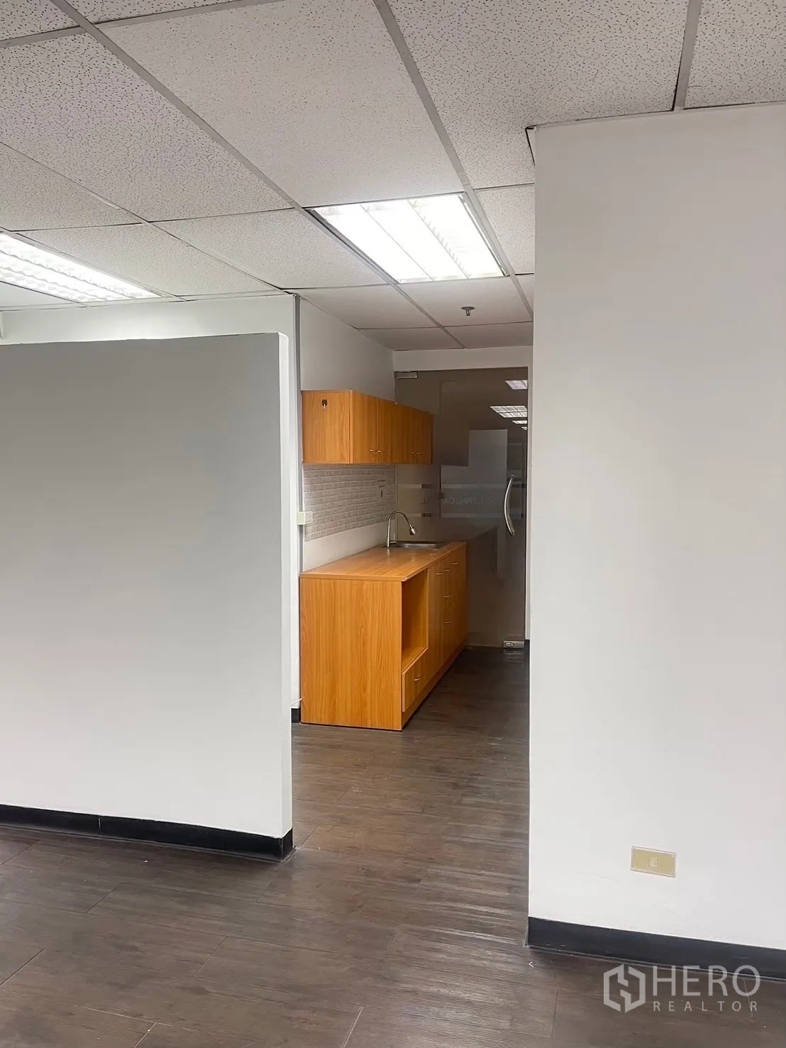 Office Space for rent in Watthana, Bangkok - Pantry area with wooden cabinets, countertop, and sink beside the workspace.