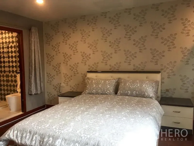 联排别墅 出租在Bang Rak, Bangkok - 卧室带纹样墙纸、双人床、床头柜，并与套内卫浴相连。