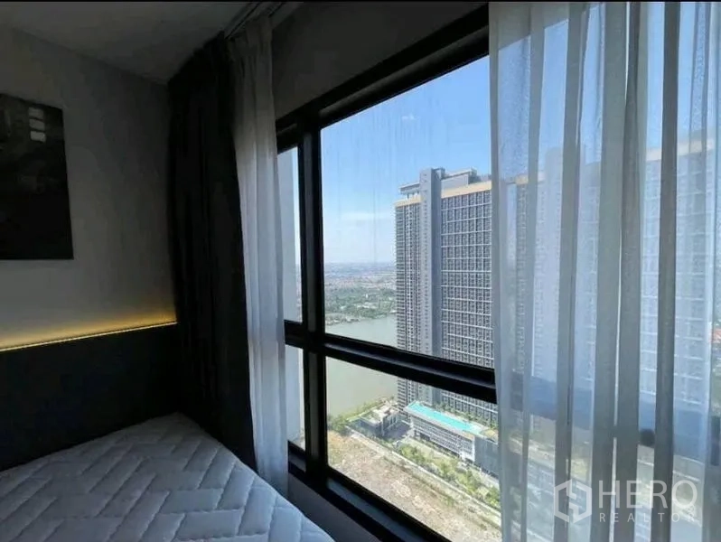 公寓 出租在Yan Nawa, Bangkok - 卧室窗外可见临近高层建筑与河景。