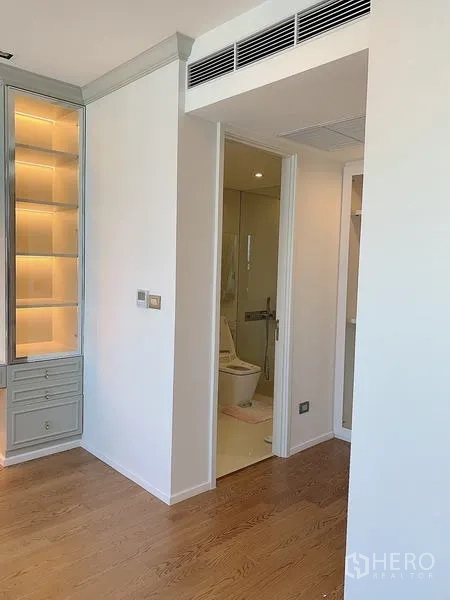 Condominium for sale - Bedroom corridor leading to modern bathroom and lit display shelves.