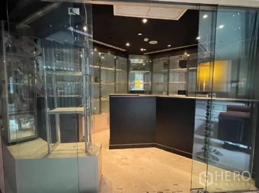 Retail Space for rent in Watthana, Bangkok - Compact retail shop interior with glass display cabinets, black ceiling spotlights, and a central counter.