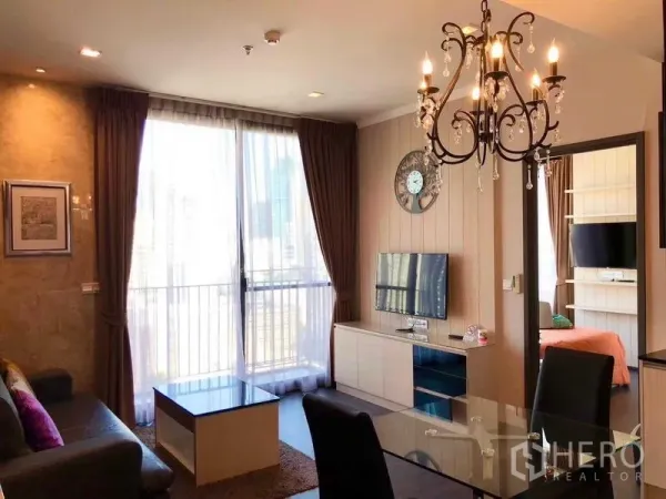 Condominium for rent or sale in Watthana, Bangkok - Bright living room with balcony doors, chandelier and wall-mounted TV
