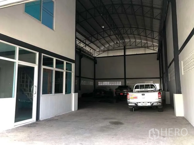 Warehouse for rent in Pak Kret, Nonthaburi - Warehouse entrance showing glass office door and covered drive-in loading space under the arched roof.