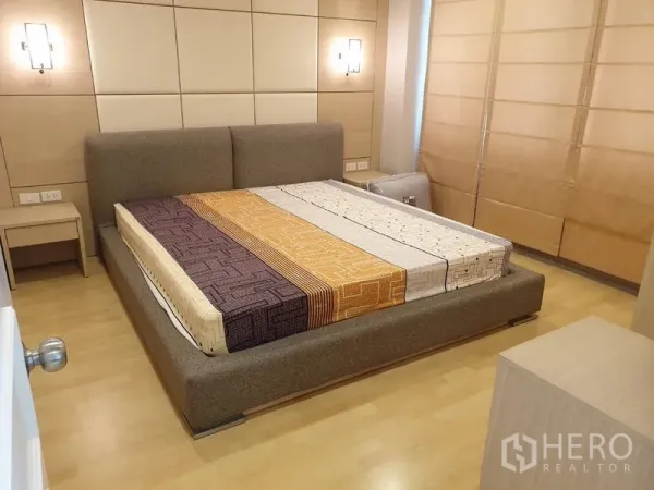 公寓 出租在Watthana, Bangkok - 温馨卧室，软包床与装饰墙面，壁灯柔和，配遮光窗帘。