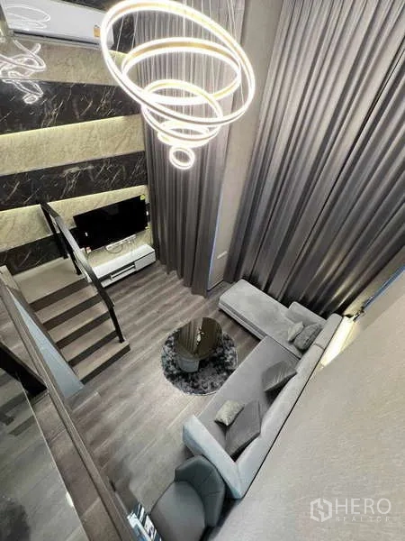 公寓 出售在Chatuchak, Bangkok - 俯瞰客厅：落地窗厚窗帘、L型沙发、茶几与环形吊灯。