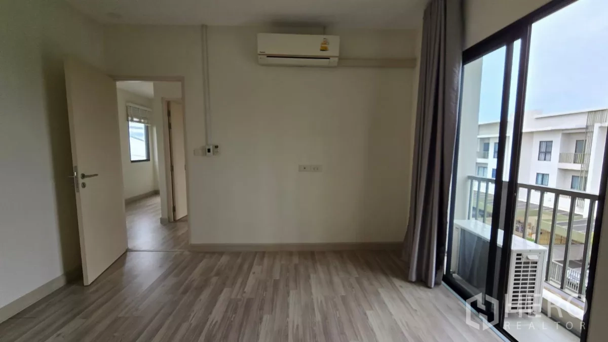 Townhouse for rent or sale in Saphan Sung, Bangkok - Bedroom fitted with air conditioner and access to balcony overlooking the project.