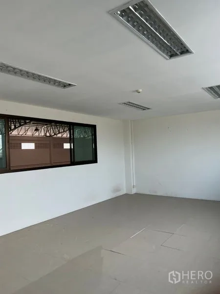 Warehouse for rent in Lat Krabang, Bangkok - Simple office room with window overlooking the warehouse and fluorescent ceiling lights.