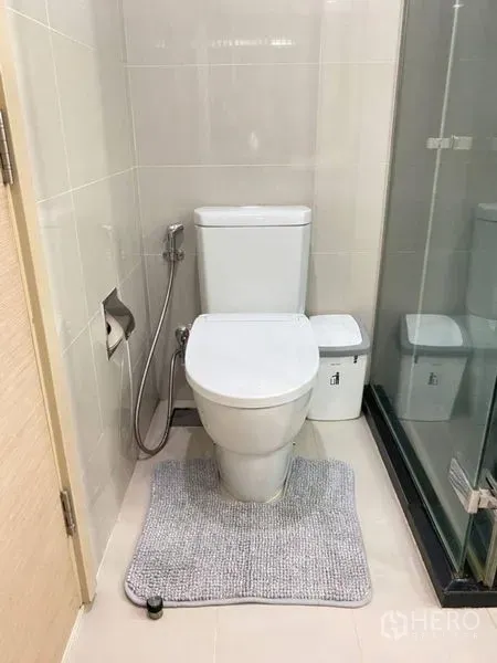 公寓 出租在Watthana, Bangkok - 马桶旁是玻璃淋浴间，浅色瓷砖墙面