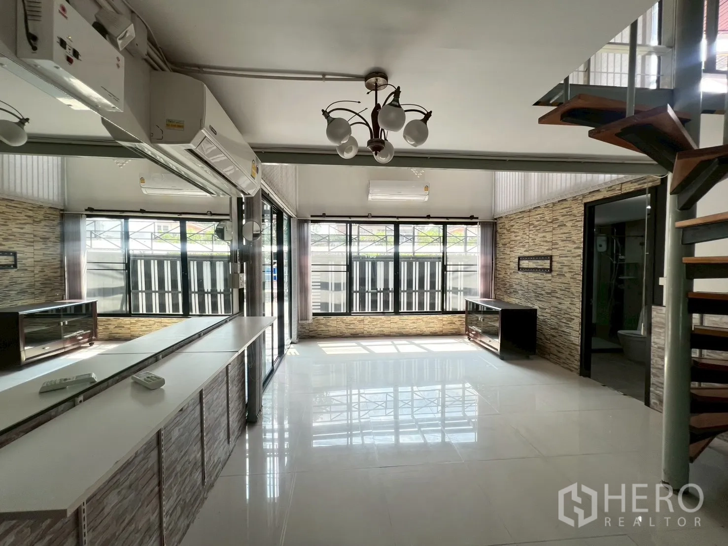 Detached House for rent or sale in Wang Thonglang, Bangkok - Sunlit living room with stone accent wall, picture windows and counter.