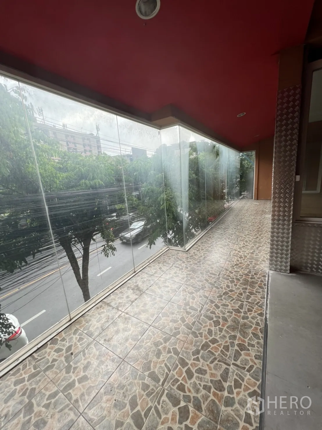 Shophouse for rent in Watthana, Bangkok - Enclosed balcony with stone-look floor tiles and floor-to-ceiling glass facing the road.