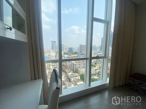 Condominium for rent in Bang Rak, Bangkok - Floor-to-ceiling corner window delivering a wide city view from the work desk.