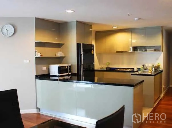 คอนโด ให้เช่าในHuai Khwang, Bangkok - ครัวรูปตัว U ตู้บิวท์อินเงางาม เคาน์เตอร์หินสีดำ พร้อมตู้เย็นและไมโครเวฟ