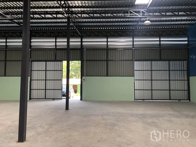 货栈 出租在Khlong Luang, Pathum Thani - 仓库内部空间宽敞，高钢桁架屋顶、混凝土地面与大型推拉门。