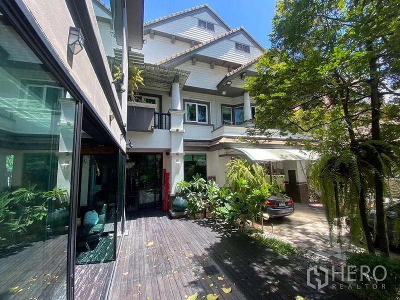 独立式住宅 出售在Suan Luang, Bangkok - 别墅外立面，木质露台、大面积落地窗与绿植。