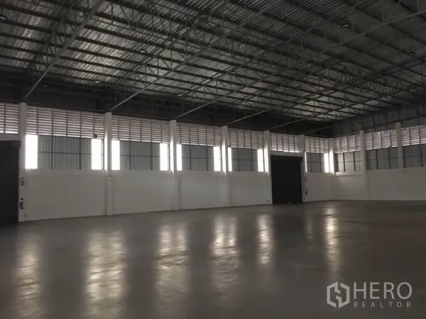 Factory for rent in Samut Prakan - Open production hall showing multiple roller doors, skylight panels and column-free warehouse space.