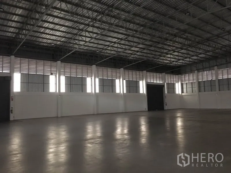 Factory for rent in Samut Prakan - Open production hall showing multiple roller doors, skylight panels and column-free warehouse space.