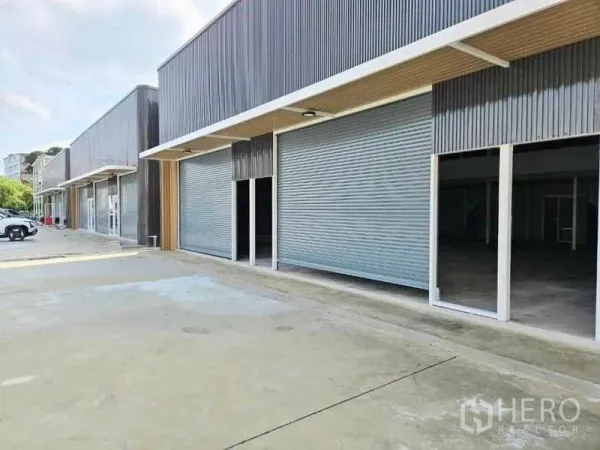 Warehouse for rent in Prawet, Bangkok - Modern warehouse row in Prawet, Bangkok with roller shutter doors and a wide concrete forecourt.