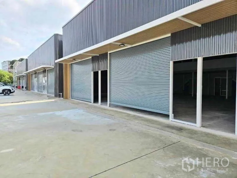 Warehouse for rent in Prawet, Bangkok - Modern warehouse row in Prawet, Bangkok with roller shutter doors and a wide concrete forecourt.