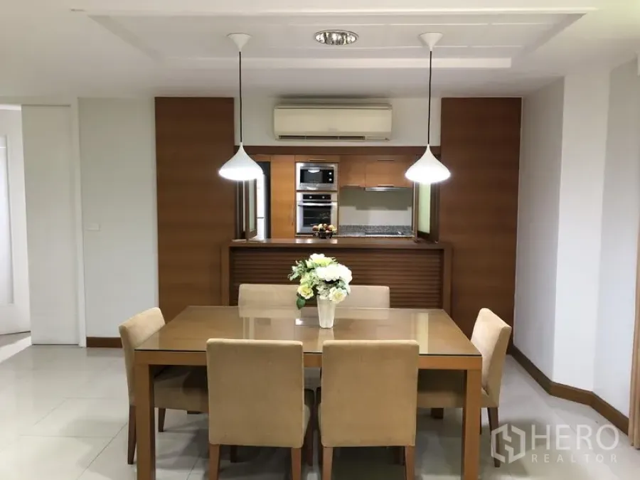 独立式住宅 出租在Watthana, Bangkok - 明亮的餐厅，吊灯与六人餐桌，面向木质厨房。