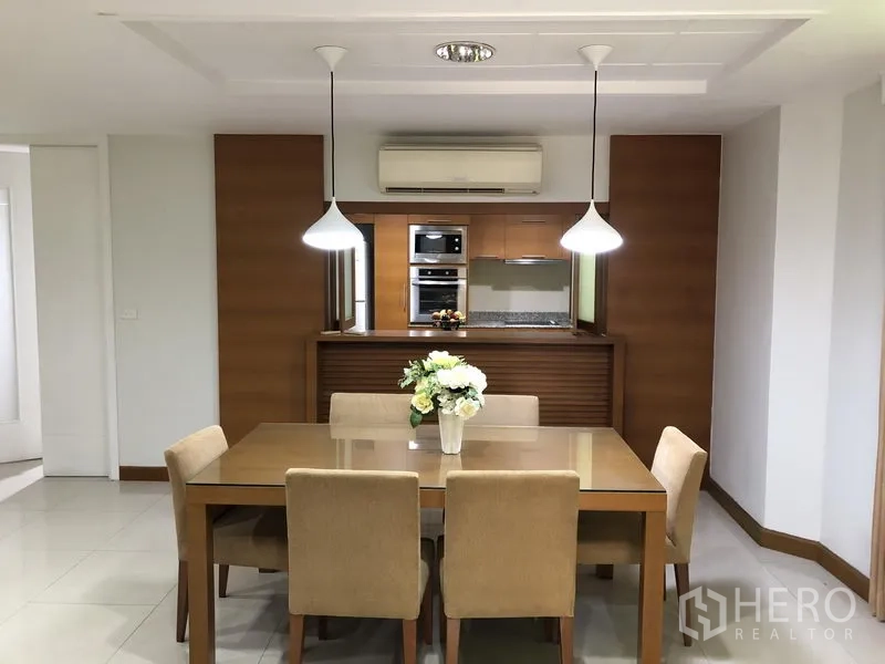 独立式住宅 出租在Watthana, Bangkok - 明亮的餐厅，吊灯与六人餐桌，面向木质厨房。