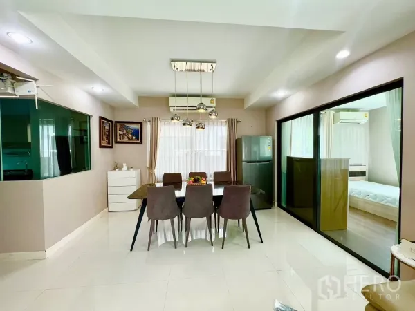 บ้าน ให้เช่าหรือขายในBang Phli, Samut Prakan - มุมทานอาหารพร้อมโคมไฟห้อย ประตูกระจกบานเลื่อน และช่องเปิดสู่ห้องครัว.