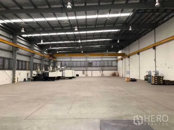 Factory for rent in Bang Sao Thong, Samut Prakan - Open warehouse floor with dual overhead cranes and roller shutter doors at the rear.