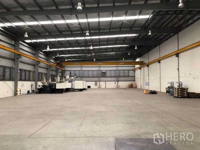 Factory for rent in Bang Sao Thong, Samut Prakan - Open warehouse floor with dual overhead cranes and roller shutter doors at the rear.