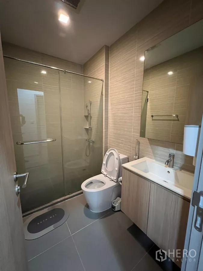 Condominium for rent or sale in Chatuchak, Bangkok - Second bathroom with glass shower enclosure, vanity cabinet and toilet.