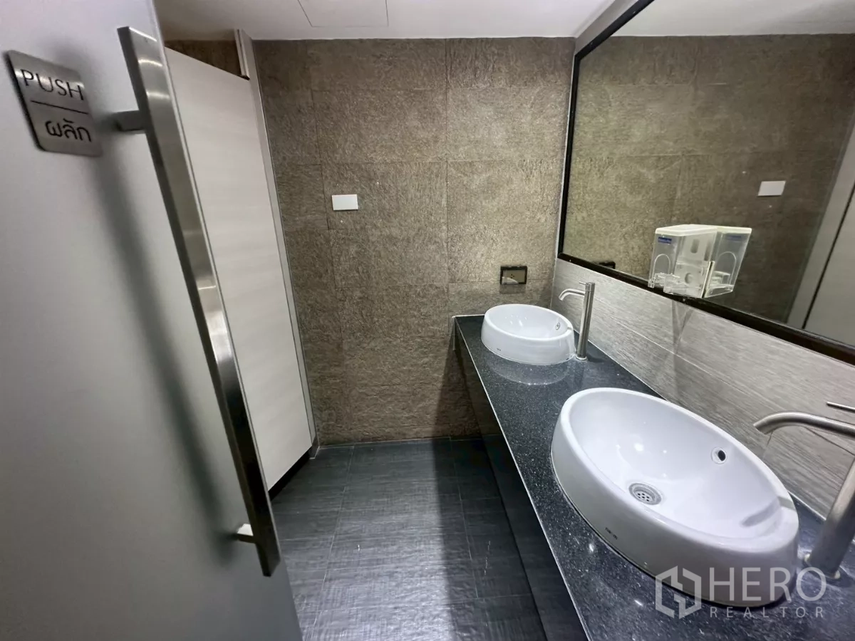 Office Space for rent in Khlong Toei, Bangkok - Modern shared restroom with double basins, mirrors and stone walls.