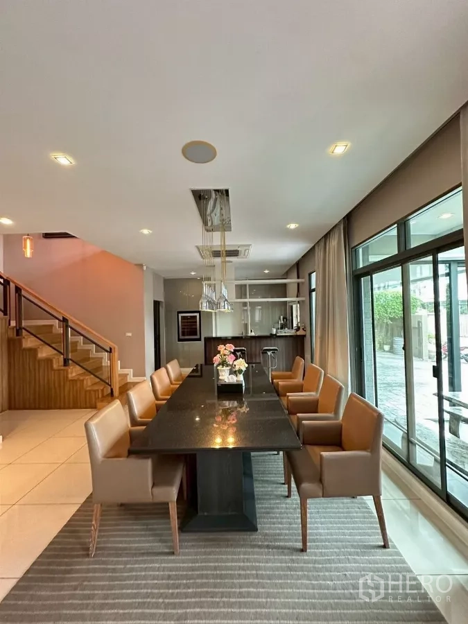 Detached House for sale in Bang Lamung, Chon Buri - Open dining room with long table for eight, pendant lights and wood staircase.