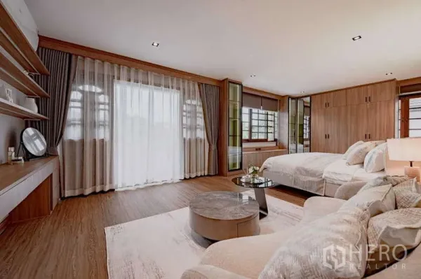 Detached House for rent or sale in Phra Khanong, Bangkok - Spacious master bedroom with wood floors, lounge area, and full-height curtains.