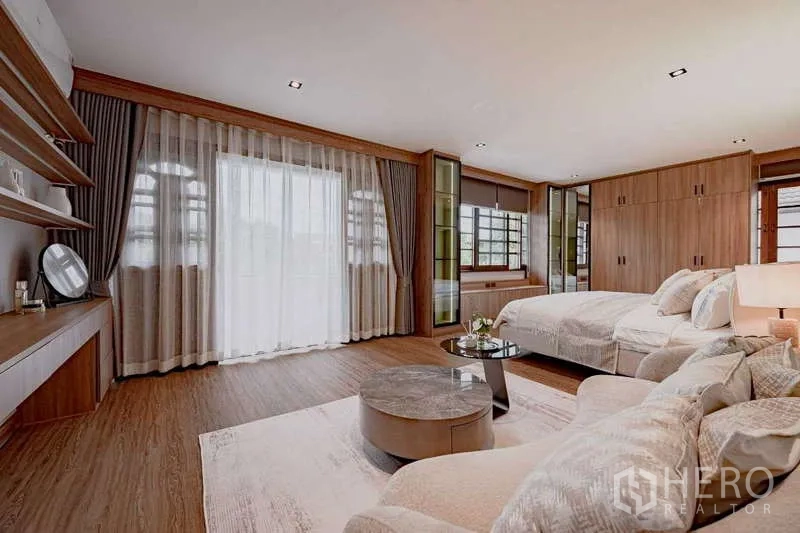 Detached House for rent or sale in Phra Khanong, Bangkok - Spacious master bedroom with wood floors, lounge area, and full-height curtains.
