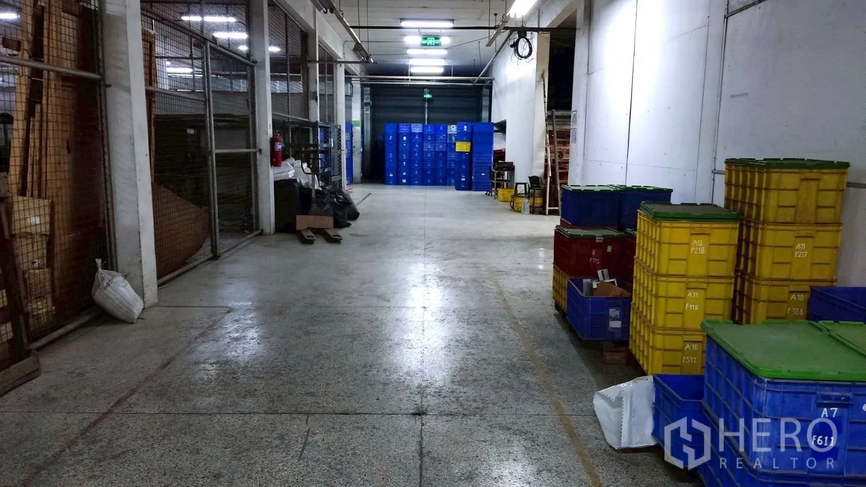 โรงงาน for sale in Lat Krabang, Bangkok - ทางเดินเก็บสินค้ามีรั้วตะแกรงและลังพลาสติกซ้อนใกล้ประตูม้วน