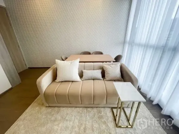 公寓 出租在Ratchathewi, Bangkok - 明亮客餐厅，米色沙发与四人餐桌，整面落地纱帘，采光充足的拉差贴威公寓。