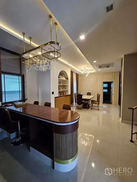 独立式住宅 出售在Mueang Pathum Thani, Pathum Thani - 吧台与吊挂酒杯架及吧椅，紧邻餐区。