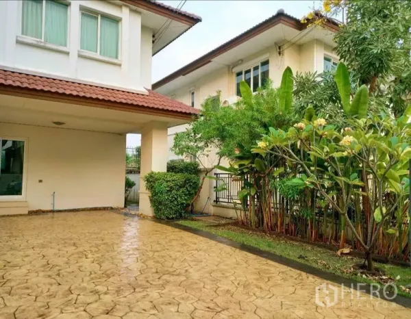 Detached House for rent or sale in Bang Yai, Nonthaburi - Paved carport and driveway beside a landscaped garden with mature trees and shrubs.